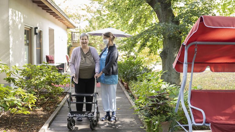 Diakonie Hospiz Wannsee - Eine Pflegerin begleitet eine Hospizgästin auf die von einem Park umgebene Terrasse des Diakonie Hospiz Wannsee. Diakonie Hospiz Wannsee - Eine Pflegerin begleitet eine Hospizgästin auf die von einem Park umgebene Terrasse des Diakonie Hospiz Wannsee.