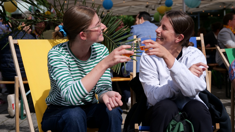 Zwei Mitarbeiterinnen stoßen mit einem Getränk beim Sommerfest in Schnelsen an