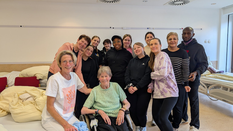 Teilnehmende des Unterrichts zum Bobath-Konzept in der Pflegeausbildung mit Dozentinnen und Übungspatientin im Schulungsraum.